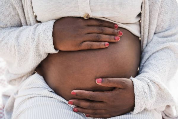 Close-up of an African pregnant woman holding her belly, symbolizing the psychological effects of pregnancy.